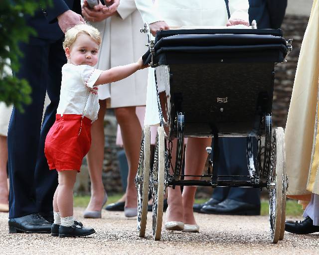 KING'S LYNN, ENGLAND - JULY 05: Prince George of Cambridge looks at his sister Princess Charlotte of Cambridge in her pram as he leaves the Church of St Mary Magdalene on the Sandringham Estate for the Christening of Princess Charlotte of Cambridge on July 5, 2015 in King's Lynn, England. (Photo by Chris Jackson/Getty Images)