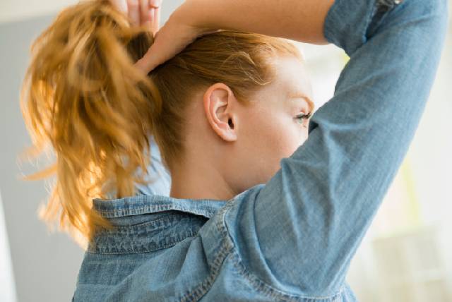 USA, New Jersey, Young woman tying hair