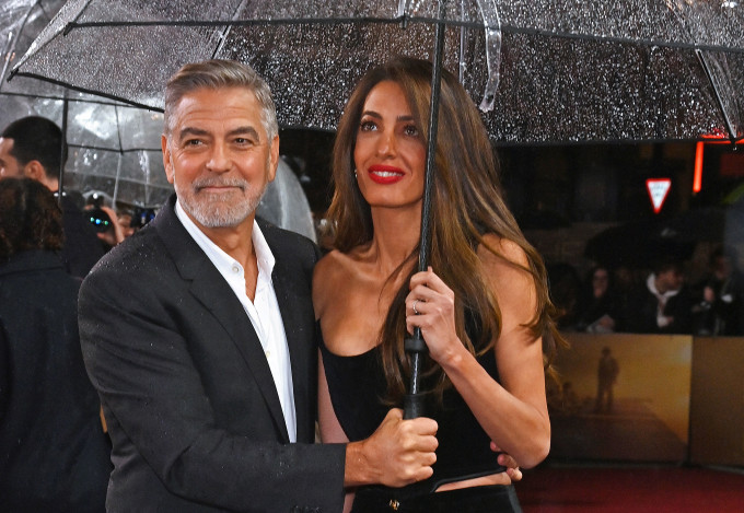 Romantikus jelenet a filmpremieren: George Clooney tartja feleségének az esernyőt, hogy az meg ne ázzon.