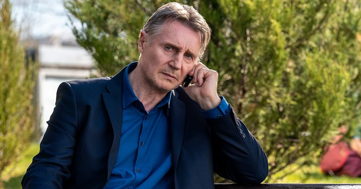 Liam Neeson ül egy padon telefonálva