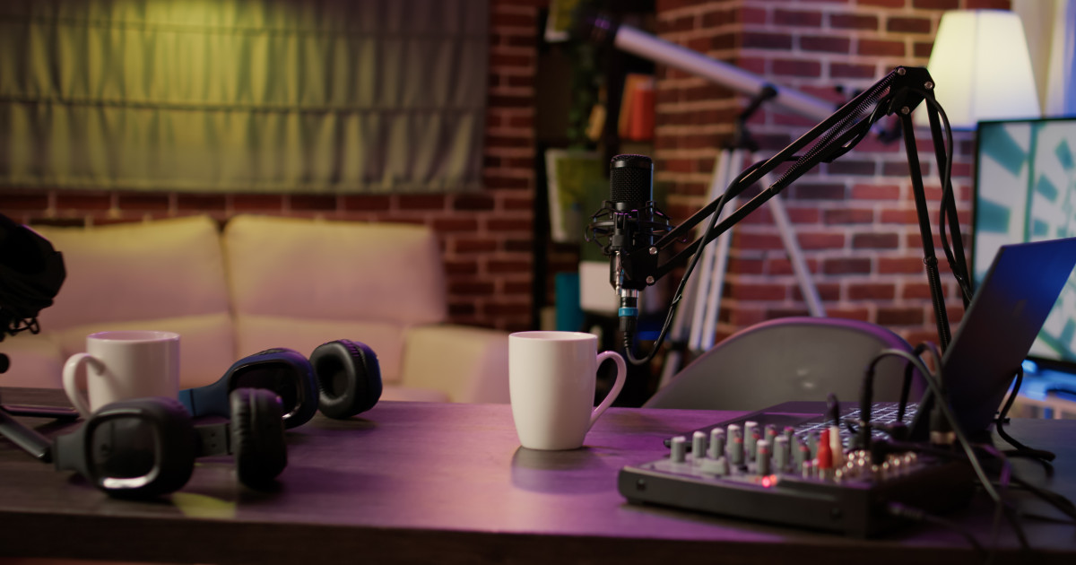 Üres podcaststúdióban berendezés mikrofonnal, kávébögrével.