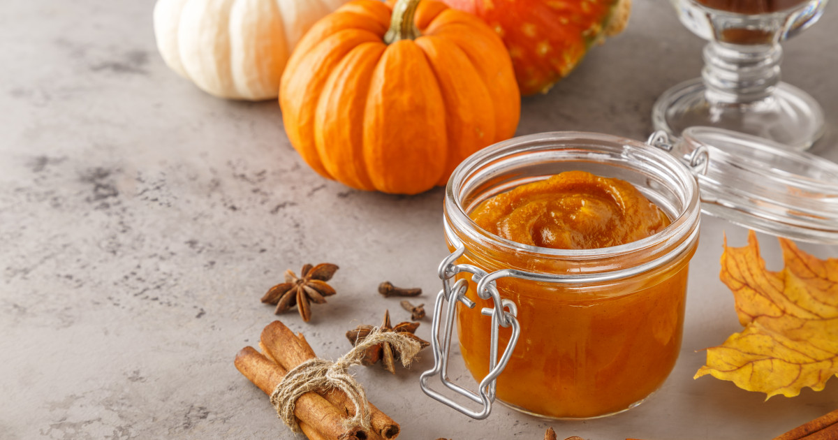 Sütőtöklekvár üvegben, háttérben tök és fűszerek.