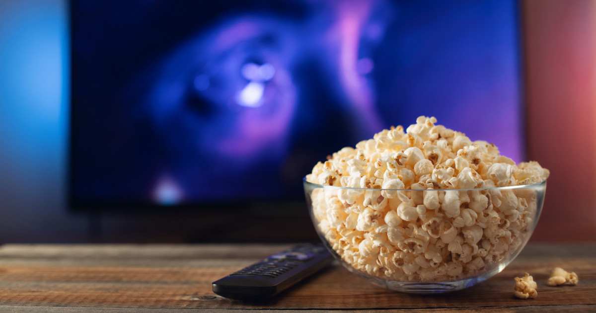 Horrorfilm a háttérben a televízión, előtte popcorn az asztalon.